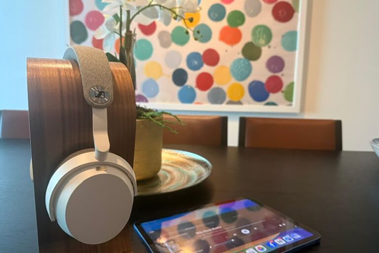 The Sennheiser MOMENTUM 5 headphones in front of a colorful Damien Hirst print.